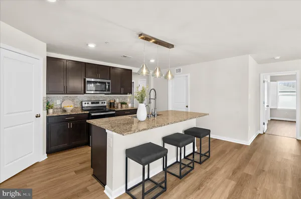 a kitchen with stainless steel appliances granite countertop a kitchen island hardwood floor sink stove dining table and chairs