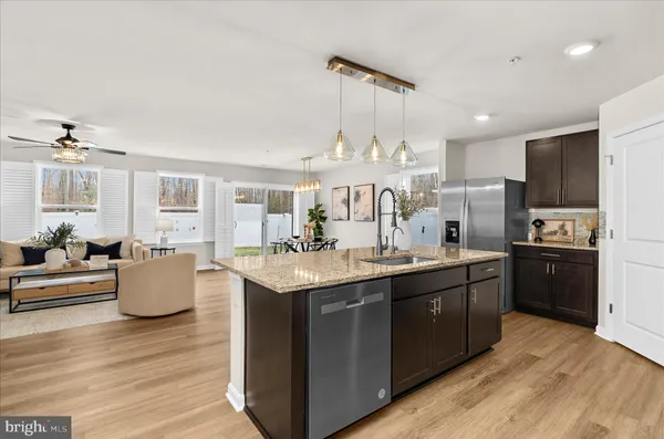 a kitchen with kitchen island granite countertop a sink cabinets and wooden floor