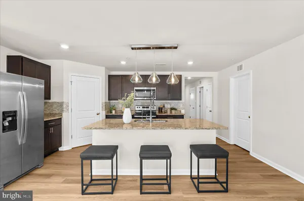 a kitchen with stainless steel appliances kitchen island granite countertop a table chairs microwave and refrigerator