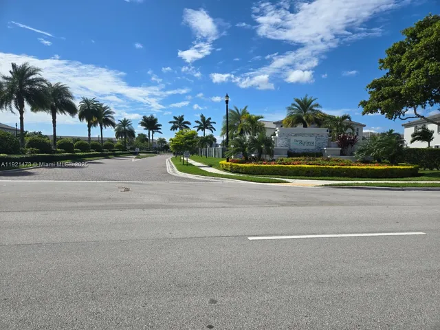 front view of house with a yard and palm trees