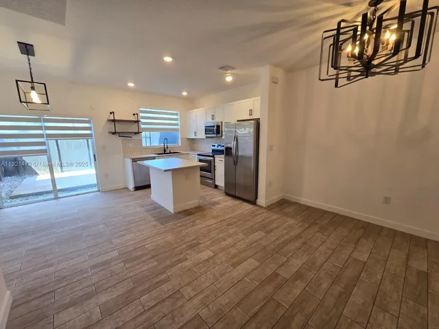 a kitchen with stainless steel appliances wooden floor and chandelier