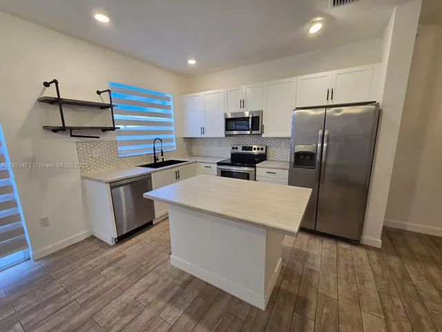 a kitchen with stainless steel appliances a refrigerator and a stove top oven