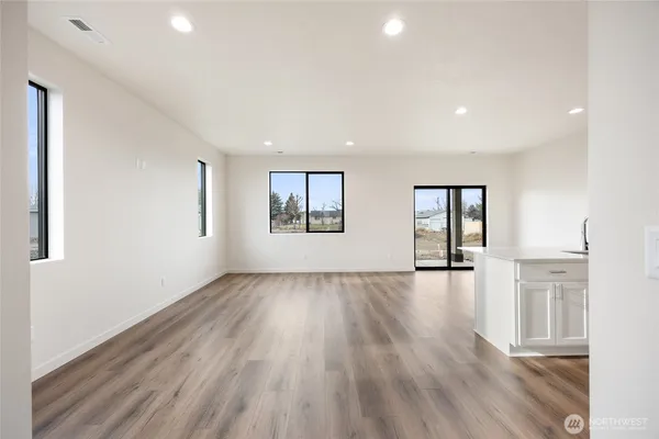 a view of kitchen with kitchen island wooden floor granite counter tops and white cabinets