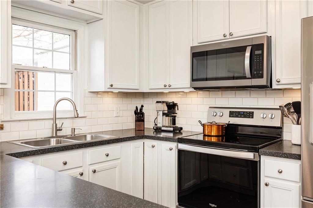 1101 Collier Road Northwest, Unit A4 Atlanta, GA 30318 - Photo 11 of 27 a kitchen with stainless steel appliances granite countertop white cabinets a stove a sink and a microwave