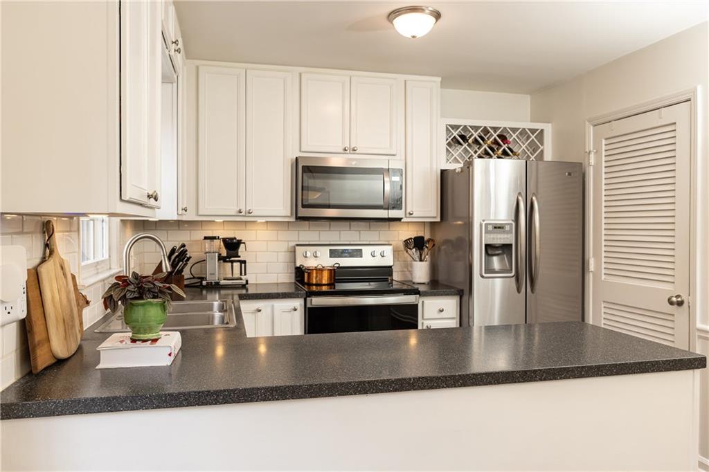 1101 Collier Road Northwest, Unit A4 Atlanta, GA 30318 - Photo 13 of 27 a kitchen with stainless steel appliances granite countertop a refrigerator a stove and a sink with wooden floor