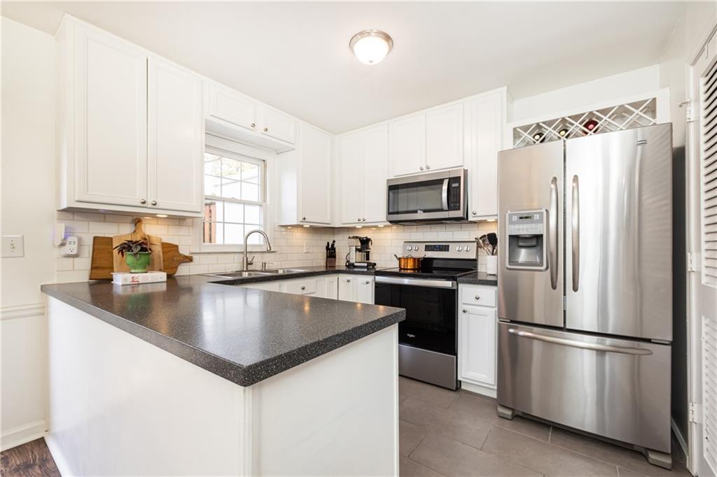 1101 Collier Road Northwest, Unit A4 Atlanta, GA 30318 - Photo 15 of 27 a kitchen with stainless steel appliances granite countertop a refrigerator a sink a stove a microwave and white cabinets