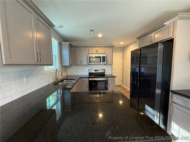 a kitchen with granite countertop a refrigerator and a stove top oven