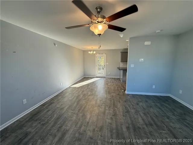 an empty room with wooden floor and a ceiling fan