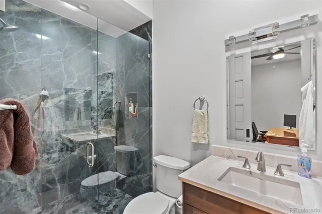a bathroom with a sink a toilet a mirror and shower