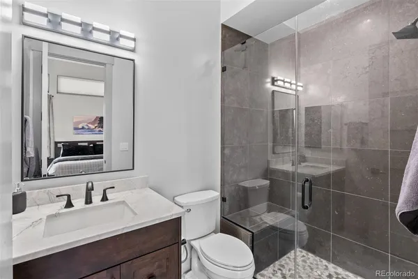 a bathroom with a granite countertop sink a toilet and shower
