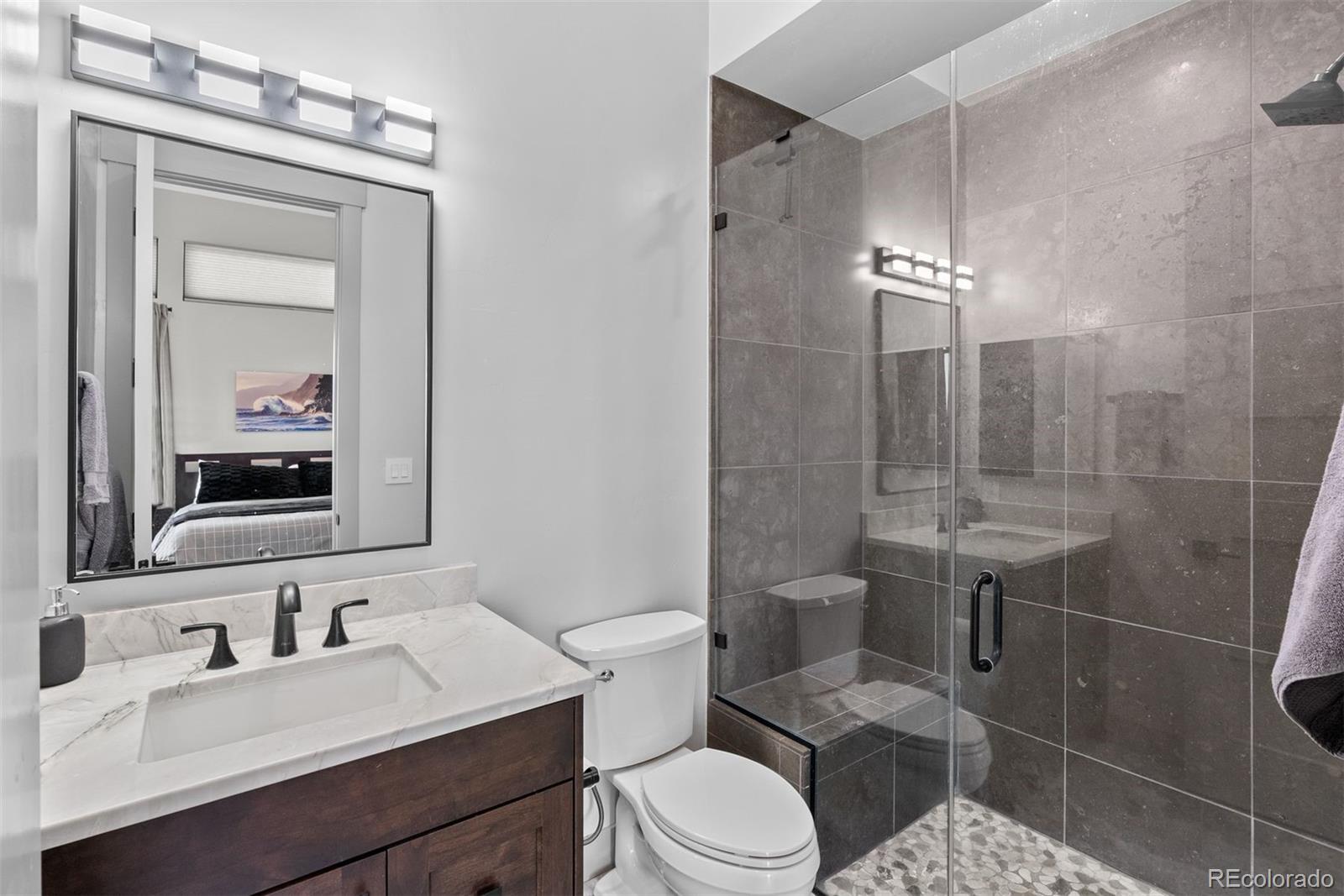 1082 West Meadow Road Evergreen, CO 80439 - Photo 33 of 50 a bathroom with a sink a toilet a mirror and shower