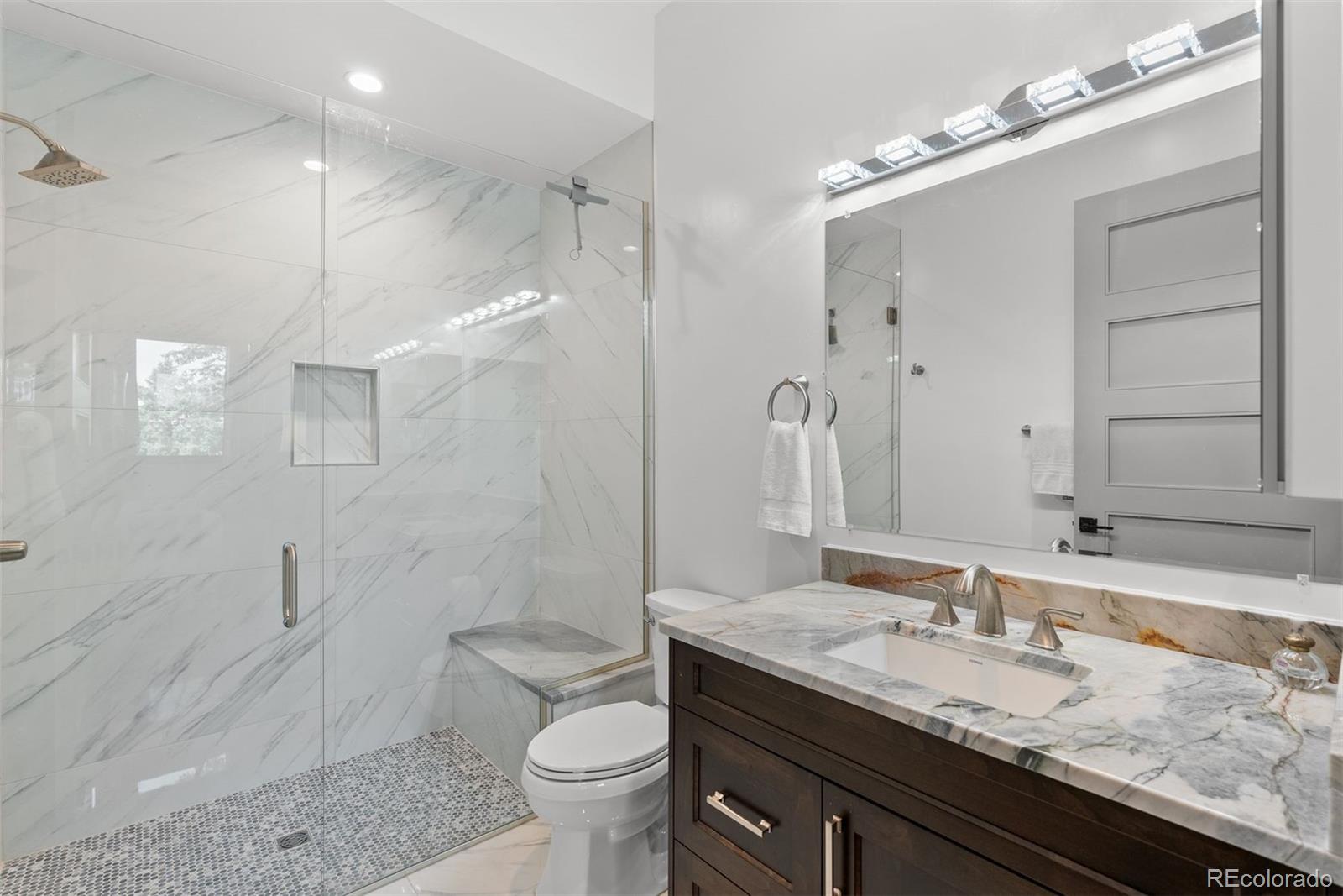 1082 West Meadow Road Evergreen, CO 80439 - Photo 36 of 50 a bathroom with a granite countertop sink a toilet and shower