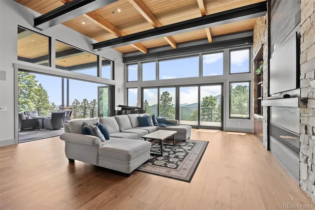 a living room with furniture large windows and wooden floor