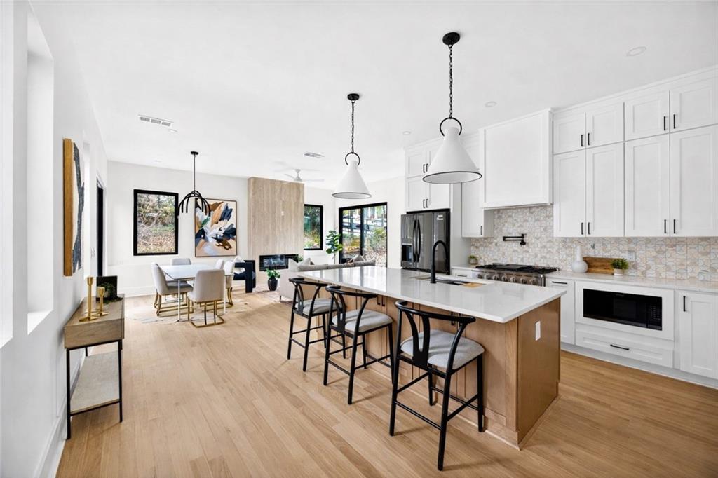1348 Finley Street Northeast Atlanta, GA 30307 - Photo 3 of 47 a open kitchen with stainless steel appliances granite countertop a stove a refrigerator a kitchen island a dining table and chairs with wooden floor