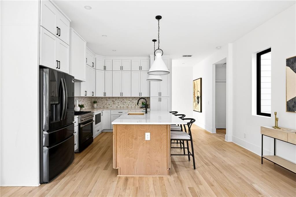 1348 Finley Street Northeast Atlanta, GA 30307 - Photo 6 of 47 a kitchen with stainless steel appliances a refrigerator a stove a sink dishwasher and a dining table with wooden floor