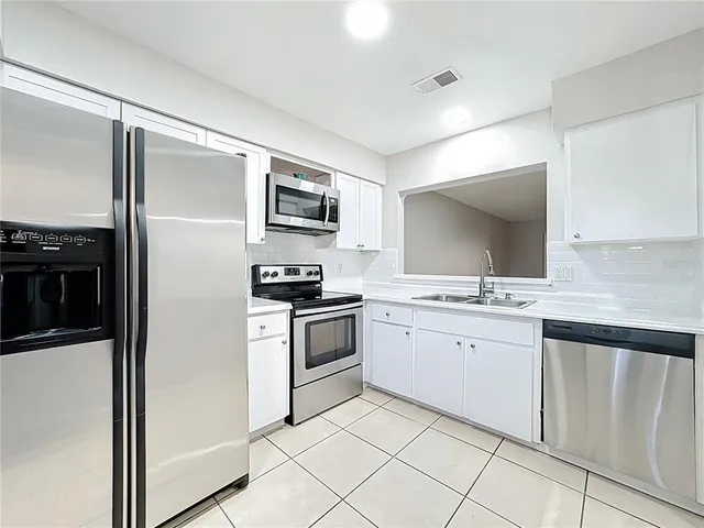 a kitchen with white cabinets and appliances