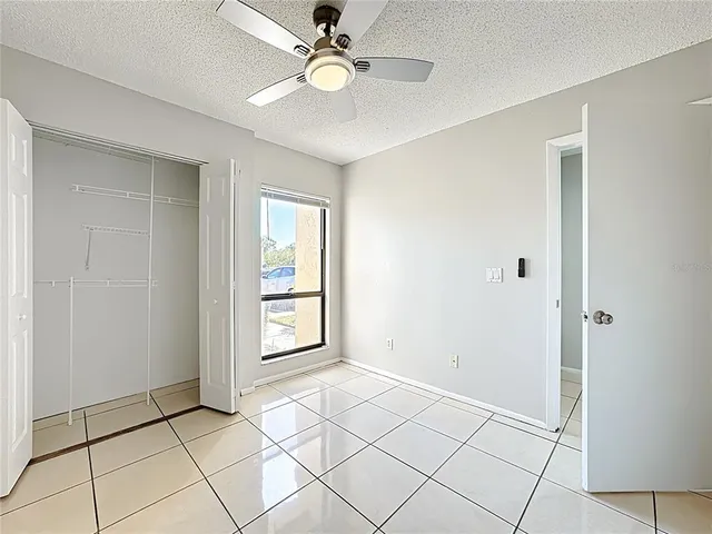a view of an empty room with window and chandelier fan