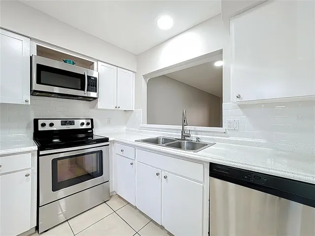 a kitchen with stainless steel appliances granite countertop a sink dishwasher a stove and a microwave oven with cabinets