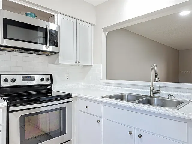 a kitchen with granite countertop a sink stainless steel appliances and cabinets