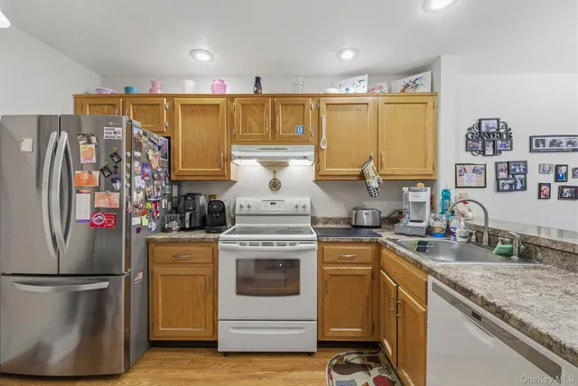 a kitchen with stainless steel appliances granite countertop a sink a stove and a refrigerator