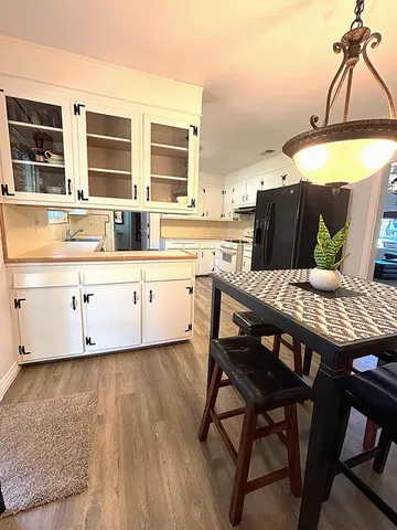 a kitchen with stainless steel appliances granite countertop a stove a sink and white cabinets with wooden floor