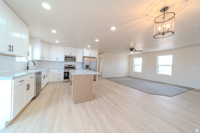 130 Pole Line Road, Unit 2 Roosevelt, UT 84066 - Photo 9 of 33 Open-concept living space with a contemporary kitchen featuring white cabinetry, subway tile backsplash, and stainless steel appliances