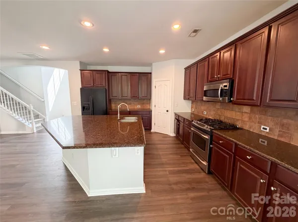a kitchen with stainless steel appliances granite countertop wooden cabinets a stove top oven a sink and dishwasher