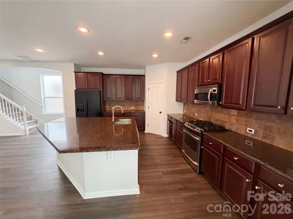 a large kitchen with stainless steel appliances and wooden cabinets