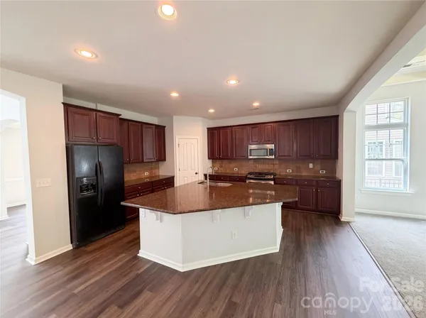 a large kitchen with stainless steel appliances granite countertop a large counter top and wooden floors