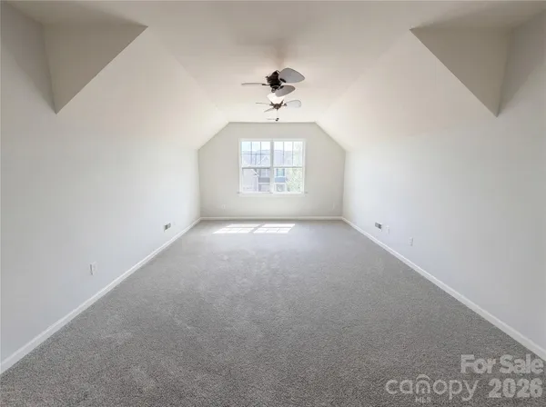 an empty room with windows and ceiling fan