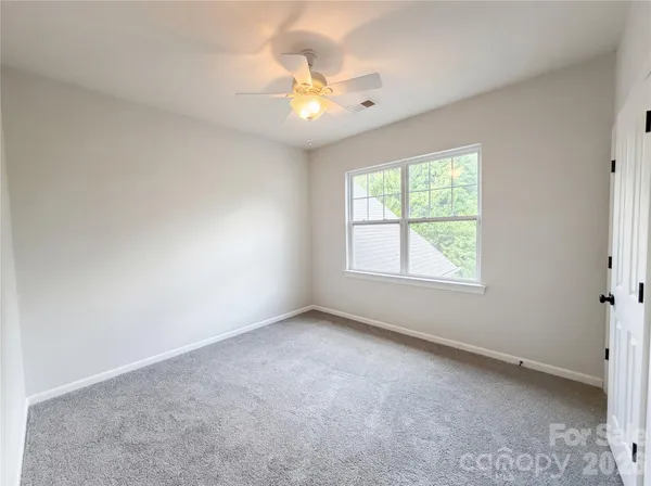 an empty room with windows and chandelier fan