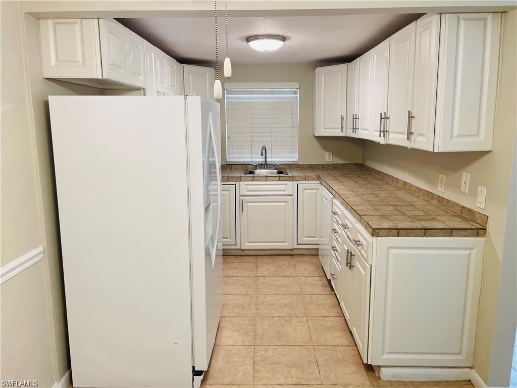 4290 Gulfstream Drive, Unit 9 Naples, FL 34112 - Photo 7 of 16 a kitchen with a sink a refrigerator and cabinets