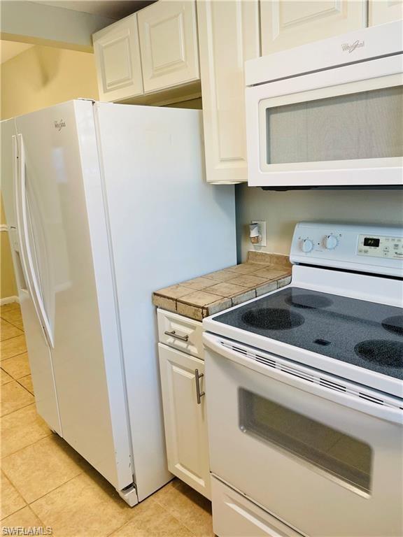 4290 Gulfstream Drive, Unit 9 Naples, FL 34112 - Photo 9 of 16 a view of washer and dryer with wooden cabinets