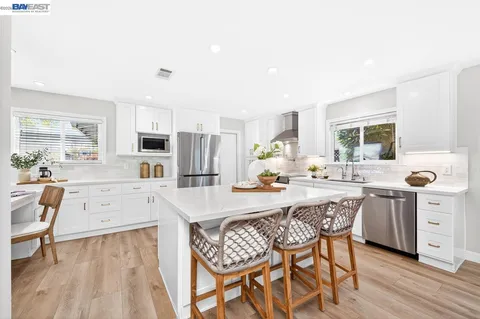 a large kitchen with granite countertop a white table and chairs