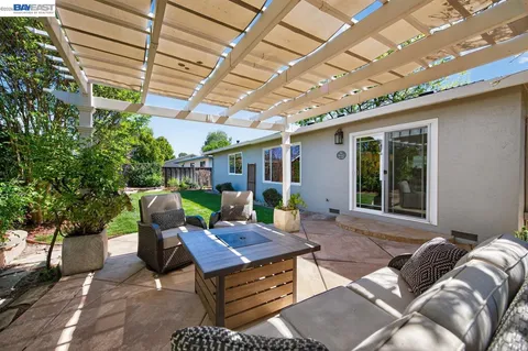 a view of a patio with table and chairs and a large tree