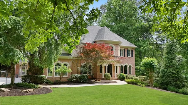 a view of a brick house with a large windows and flower plants