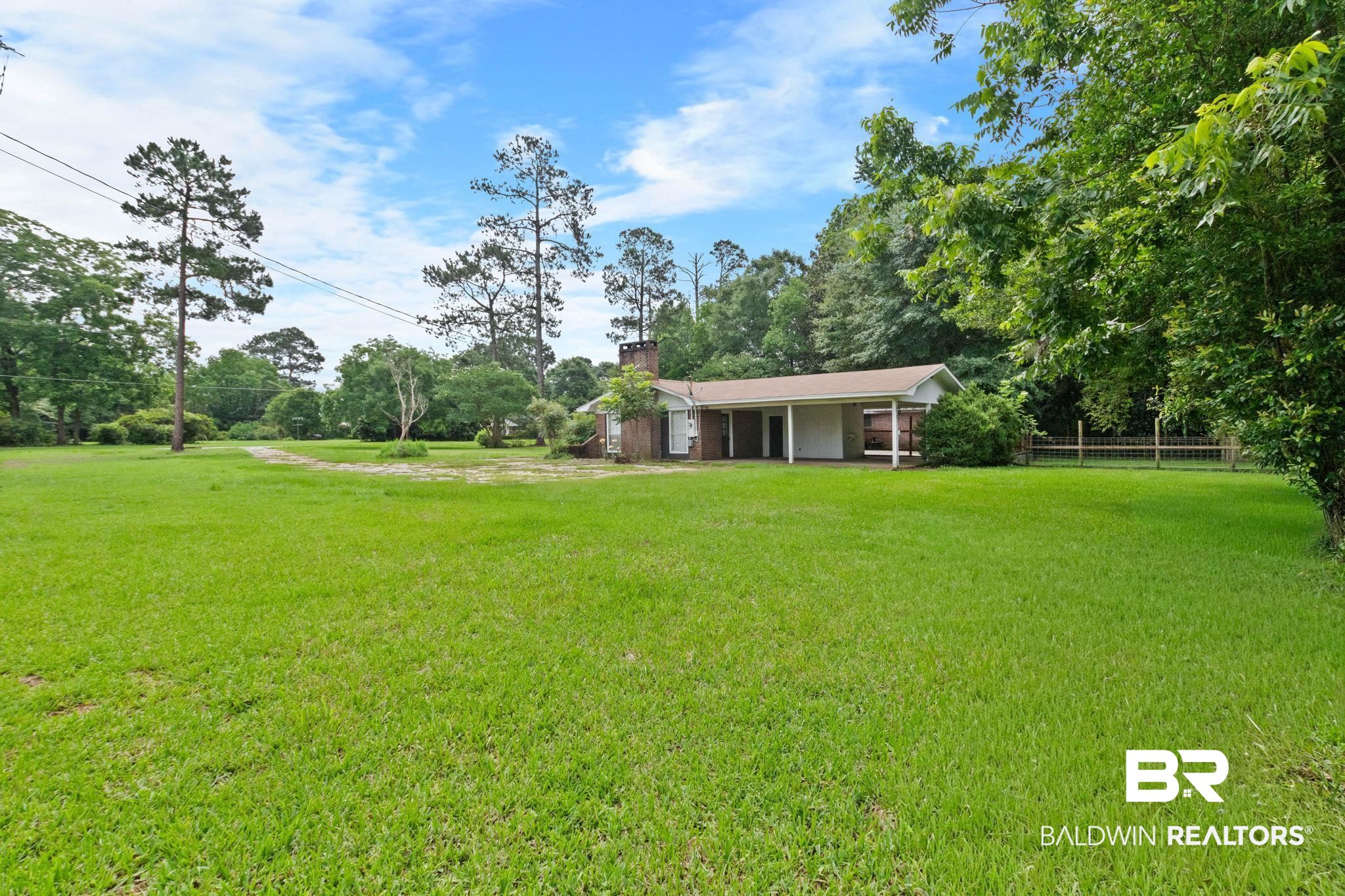 384 Old Bratt Road Atmore, AL 36502 - Photo 64 of 64 Expansive grassy lawn surrounds a single-story residence with a brick exterior and a covered carport