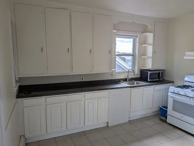 a kitchen with granite countertop white cabinets and sink