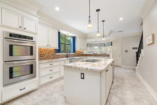 a kitchen with kitchen island granite countertop a stove oven and a sink with cabinets