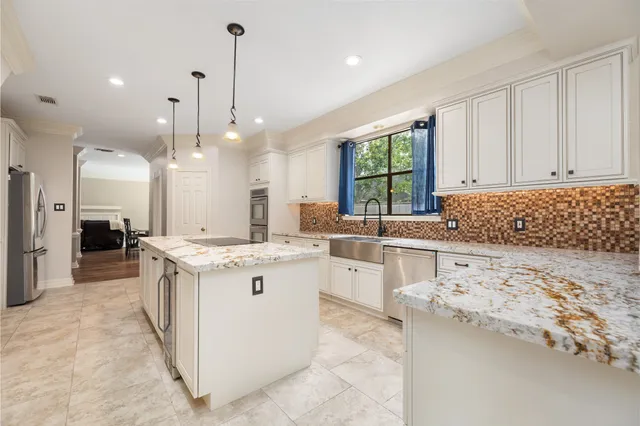 a kitchen that has a lot of white cabinets and stainless steel appliances