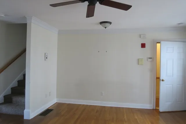 an empty room with wooden floor and chandelier fan