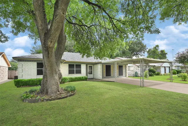 a front view of a house with a garden and trees