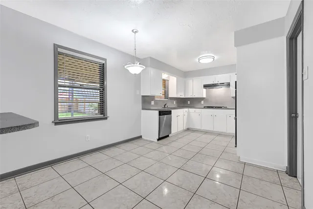 a kitchen with white cabinets and window
