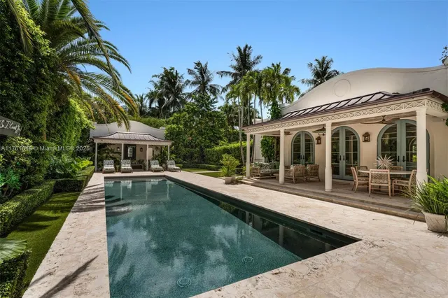a view of a white house with a swimming pool and sitting area