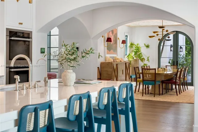 a kitchen with stainless steel appliances kitchen island granite countertop a stove a sink dishwasher and white cabinets with wooden floor