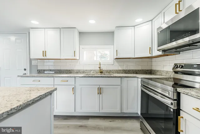 a kitchen with granite countertop white cabinets stainless steel appliances and a sink