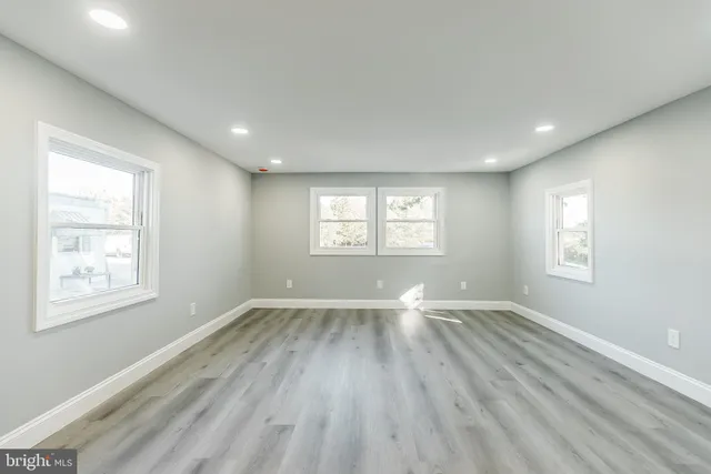a view of an empty room with wooden floor and window