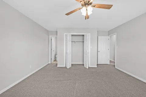an empty room with windows and chandelier fan