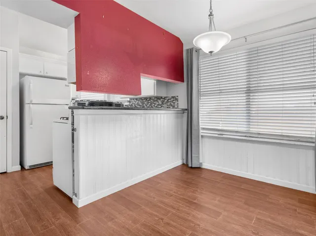 an empty room with wooden floor and chandelier