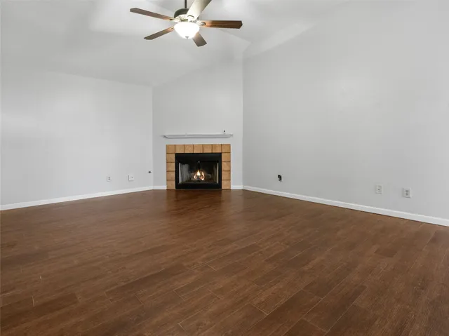 a view of an empty room with wooden floor and a fireplace